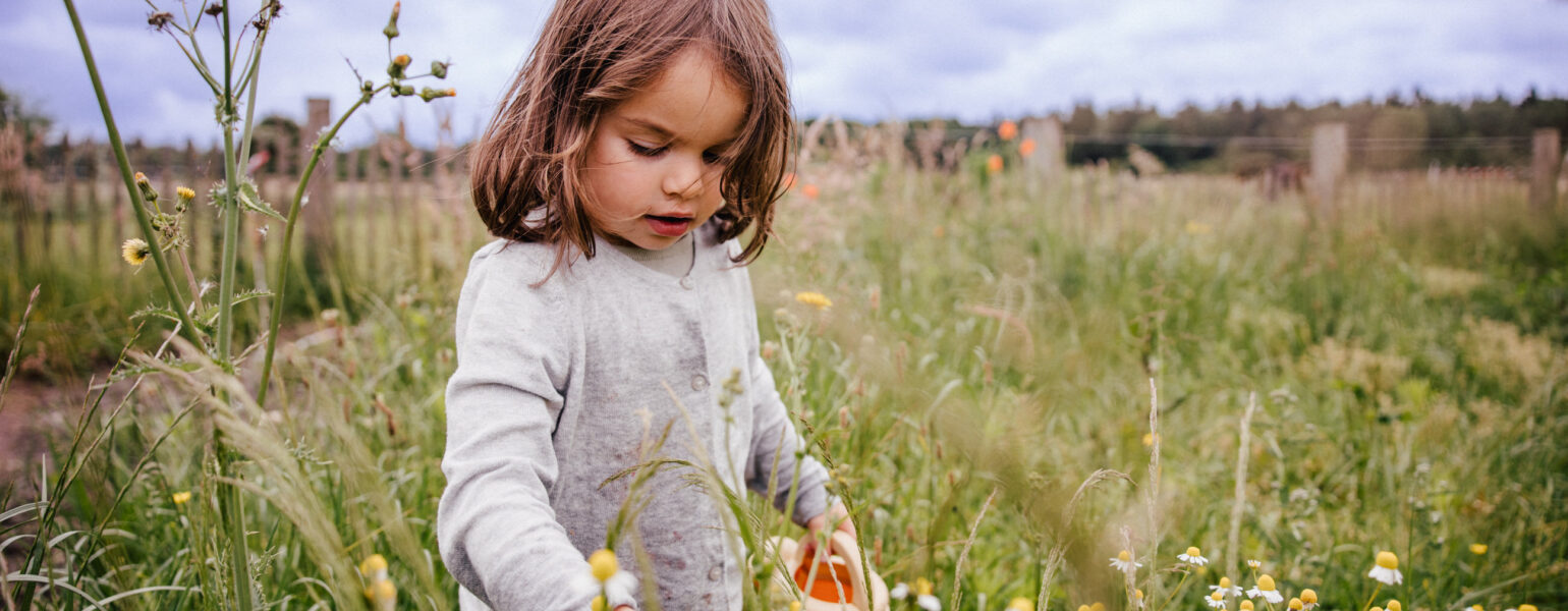 Mädchen steht in einer Blumenwiese