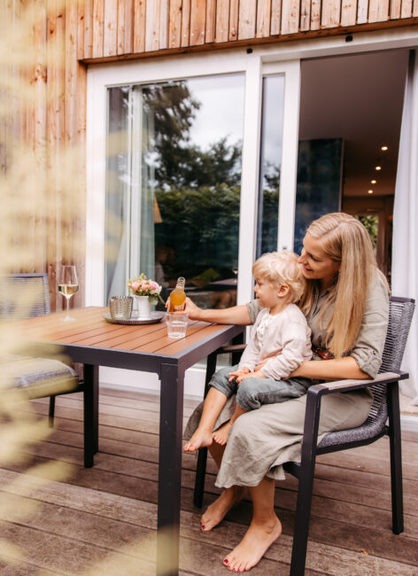 Mutter sitzt mit Sohn auf dem Schoss auf der Terrasse